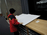 Looping animated GIF made up of photos of a person turning the pages of a very large book.