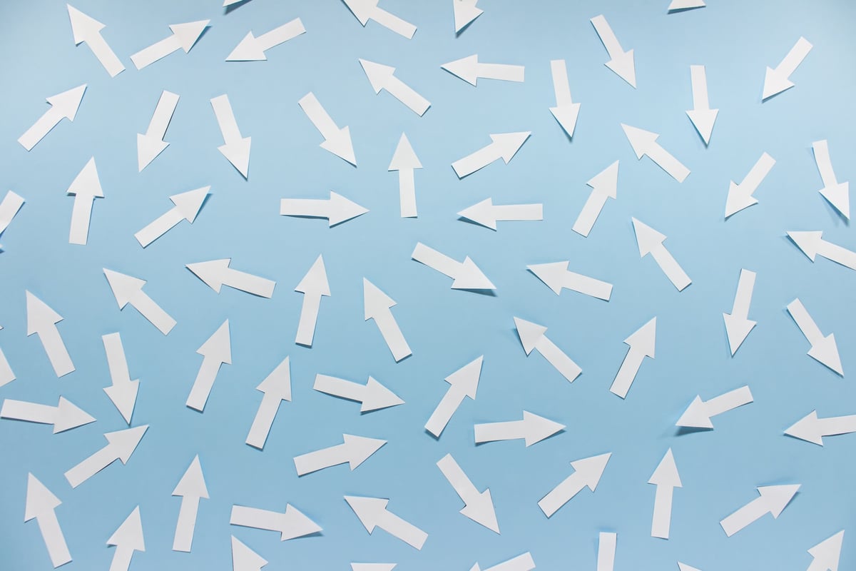 Image of many white arrows pointing in every direction against a light blue background.