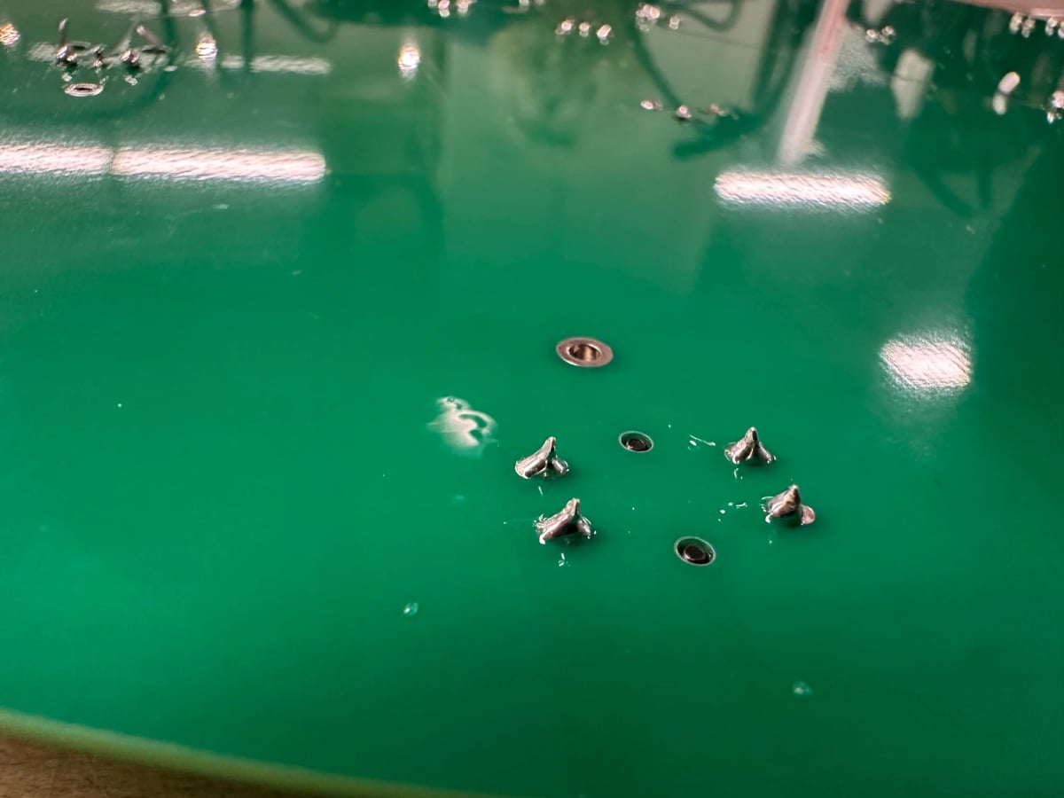Some okay soldering work. Little metal peaks coming out of a green PCB.