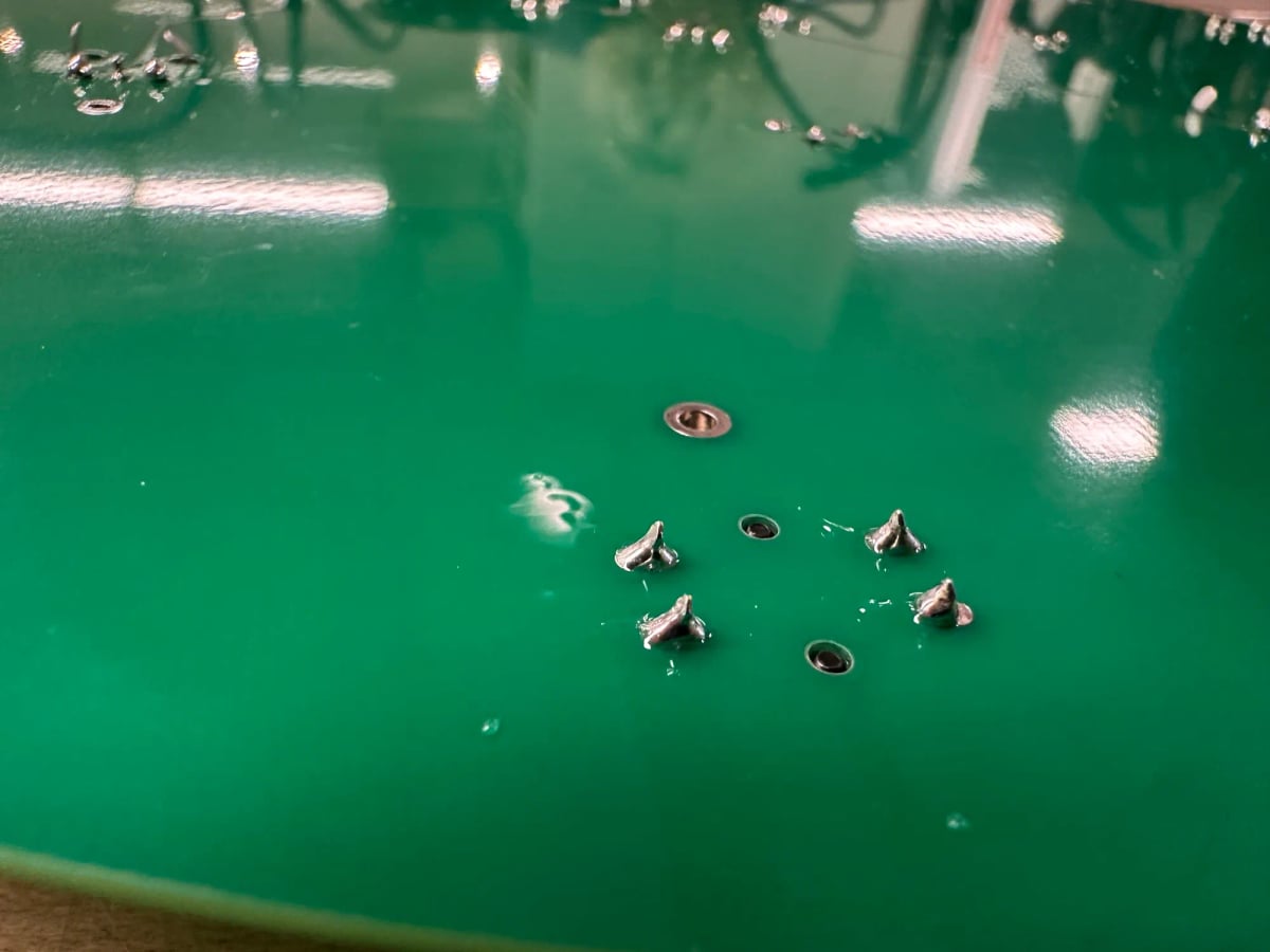 Some okay soldering work. Little metal peaks coming out of a green PCB.